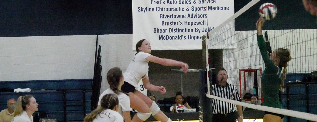 Girl&#39;s volleyball game. A player is spiking the ball.